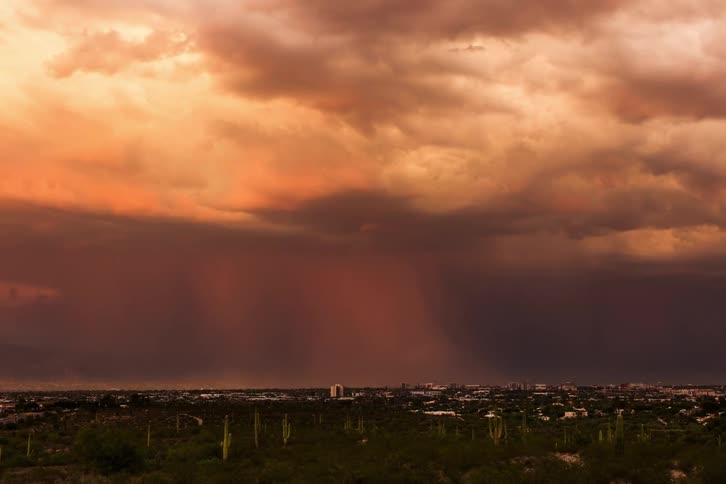 A large and dense lightning storm passing over a city from day to night