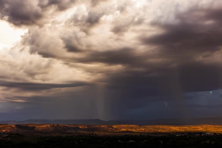 Time lapse of a gust of rain falling over a flat desert landscape