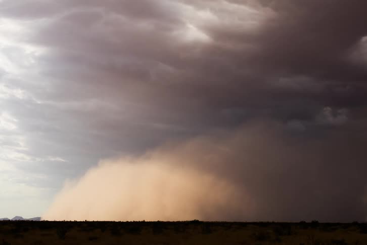 Large dust storm approaches under a cloudy sky