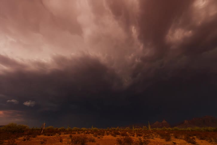 A sky with many clouds and an orange color and then it starts to get dark and a strong lightning storm forms