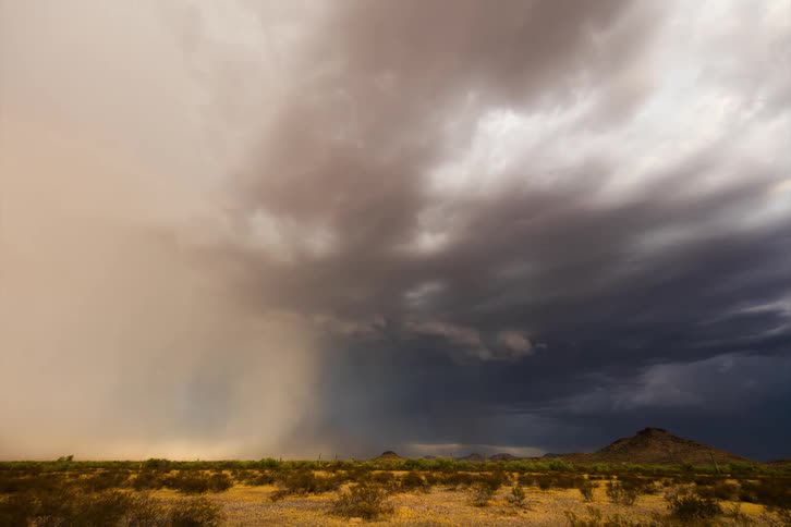 Time lapse of a gust of rain falling over a flat desert landscape