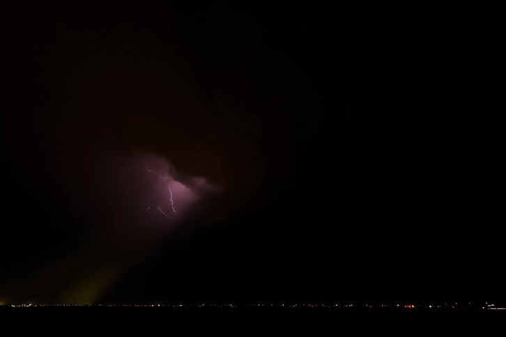 A strong storm of bright lightning in a dark sky falling on a city