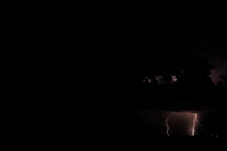 A bright lightning storm in the sky in a completely dark region