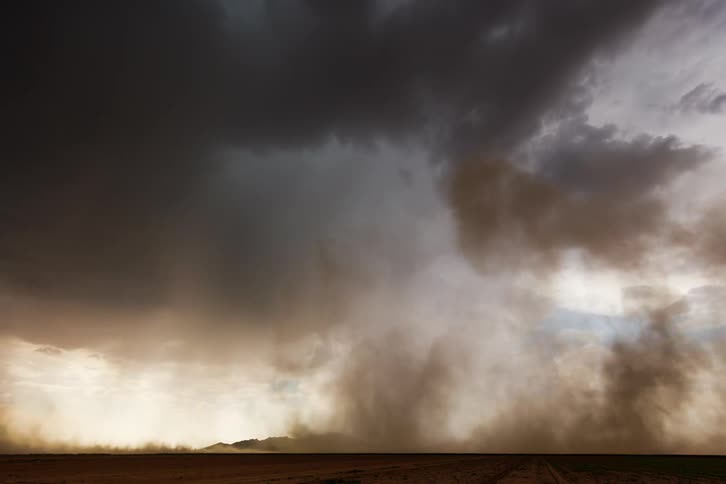 A strong tornado hitting an empty ground on a day with the sky overcast and partially dark