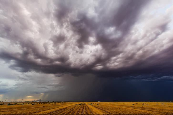 Vehicle moves through countryside while lightning strikes during a large thunderstorm