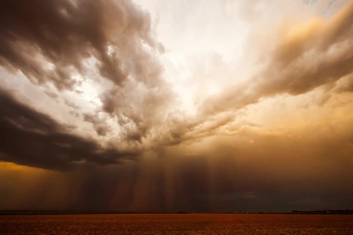 Storm clouds roll over a wide open field in the afternoon