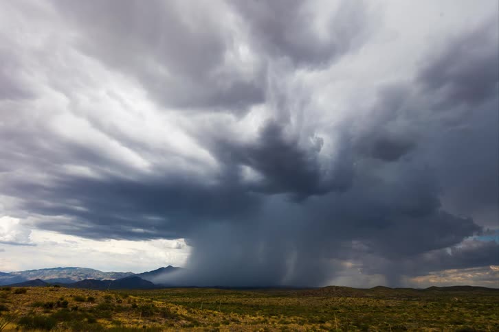 Time lapse of a gust of rain falling over a flat desert landscape