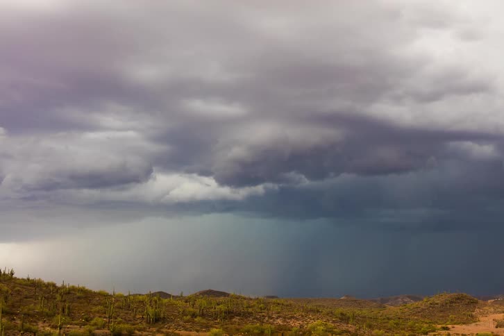 Time lapse of a gust of rain falling over a flat desert landscape