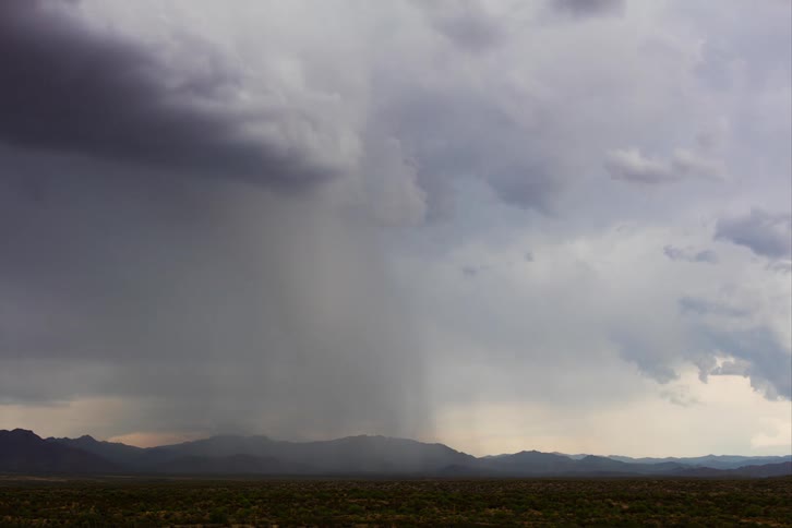 Dark storm clouds dump heavy rain over a mountainous area