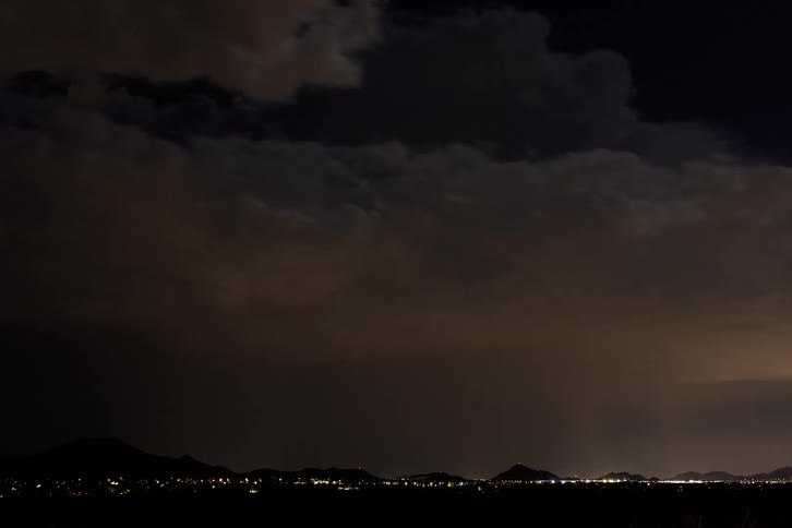 A storm of lightning and clouds passes quickly over a city at night