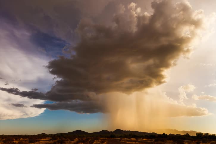 The large storm cloud pouring rain as it travels over the landscape