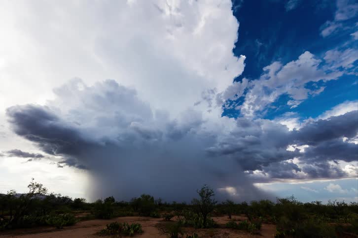 A gray storm cloud passing through a desert sky