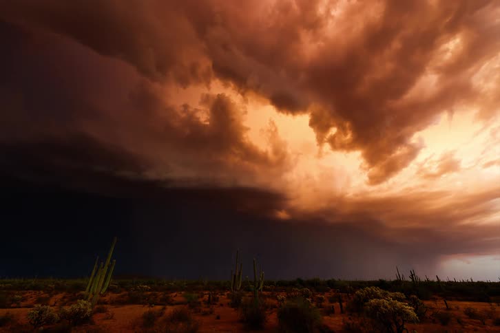 A lghtning storm coming from orange clouds in the sky on a desert dusk