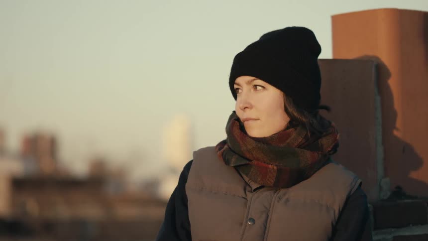 Woman wearing a scarf staring off on a cloudy day