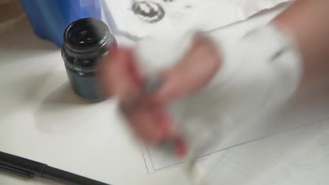 A woman painting a dog sketch using black ink