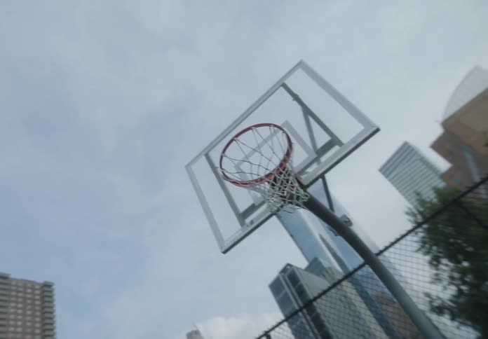 Friends play basketball at an outdoor court near downtown
