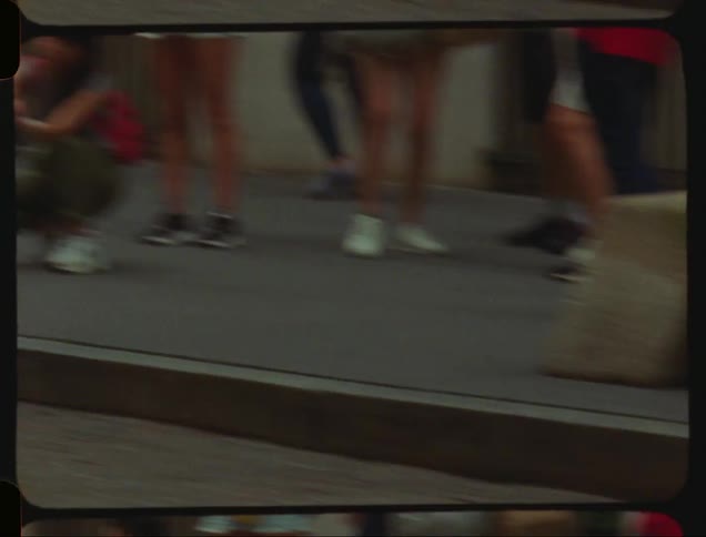 Woman takes a picture of the bronze sculpture of a child while a pedestrian walks past it