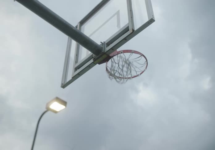 A basket ball flies through the air to hit the net from afar