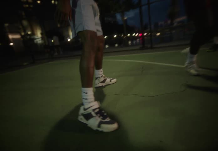 Legs of some men playing basketball on a court at night