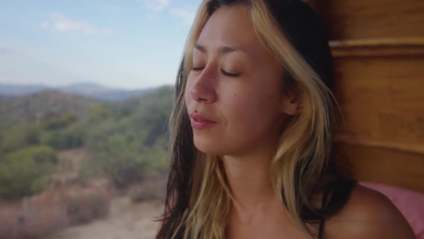 Portrait of a young woman inside a cabin next to wooded hills