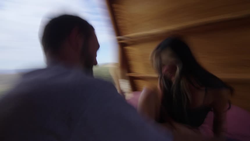 A young couple playfully tickling each other on a small hut in the mountains