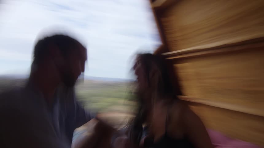 Man and woman sitting facing each other holding hands talking inside a cabin on a hill