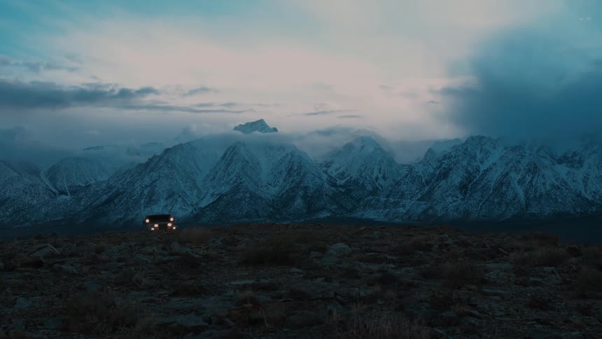 A jeep is driving off road away from the mountains