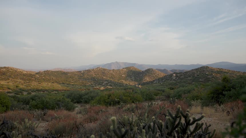 Rolling hills are covered with short vegetation on a partly sunny day