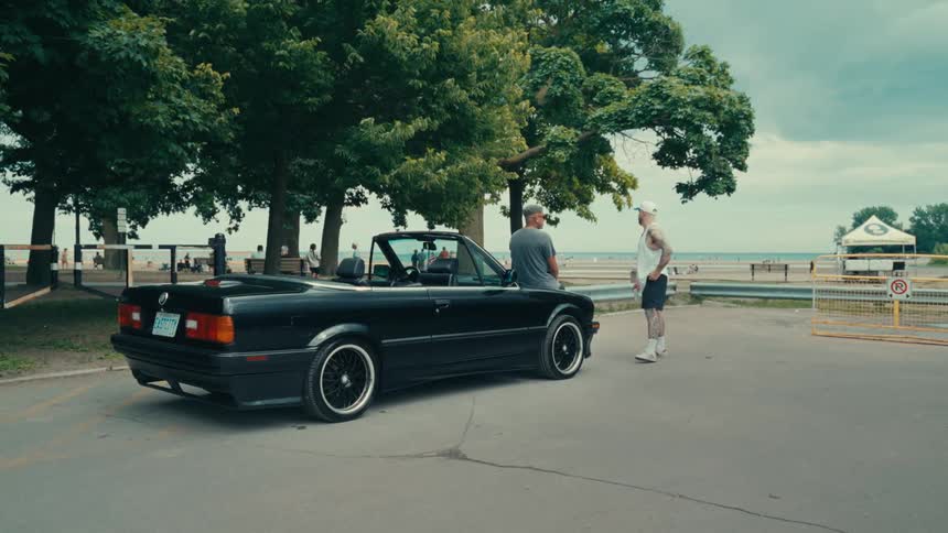 Vintage black convertible car parked and in front two men talking
