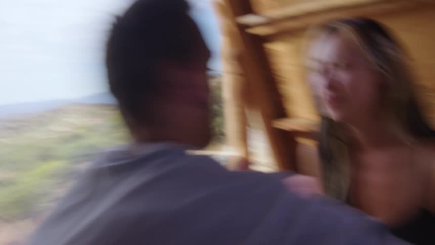 Woman and man sitting in a camping cabin playing and kissing