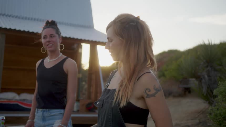 Friends grilling food near a shack in the mountains at sunset