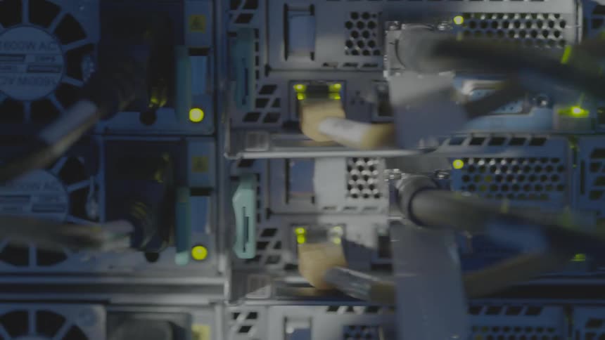 Various computer hardware and cables connected and there is a shadow passing through them
