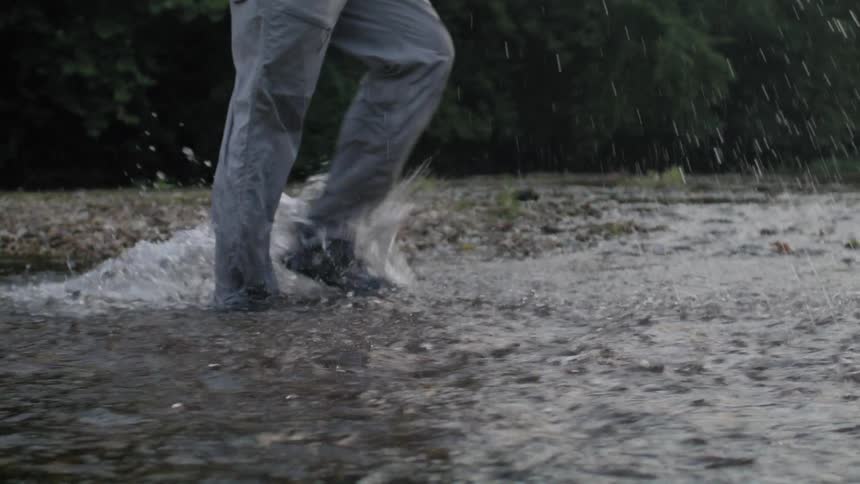 Person in pants walking by a river