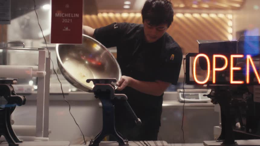 View from outside a restaurant of a man with a metal basin pouring oil