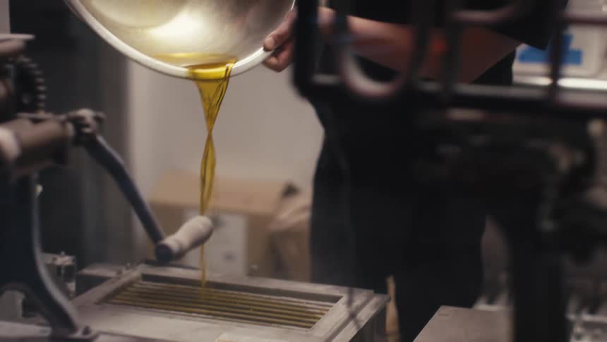 A restaurant worker pours liquid from a large metal bowl