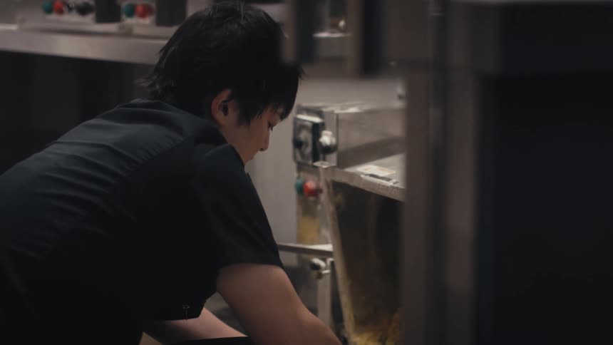 A chef is working with a pasta machine in a restaurant kitchen