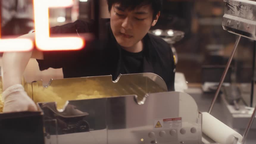 A man is mixing food in a machine at a restaurant