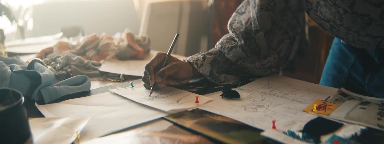Persons hand drawing on a white sheet of paper on a table