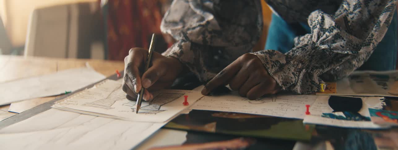 Closeup of a designers hand carefully drawing miniature dress sketches