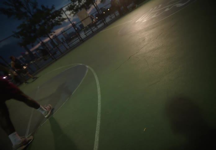 People playing basketball on an outdoor court at night