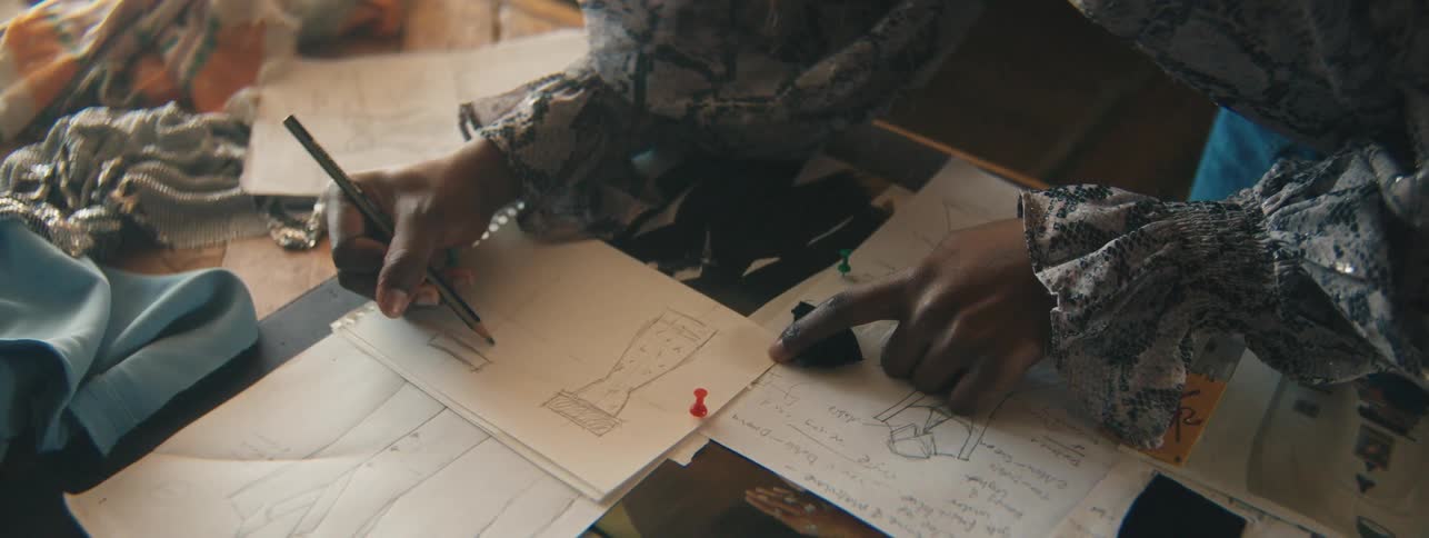 Pair of womans hands holding a pencil and drawing fashionable clothes