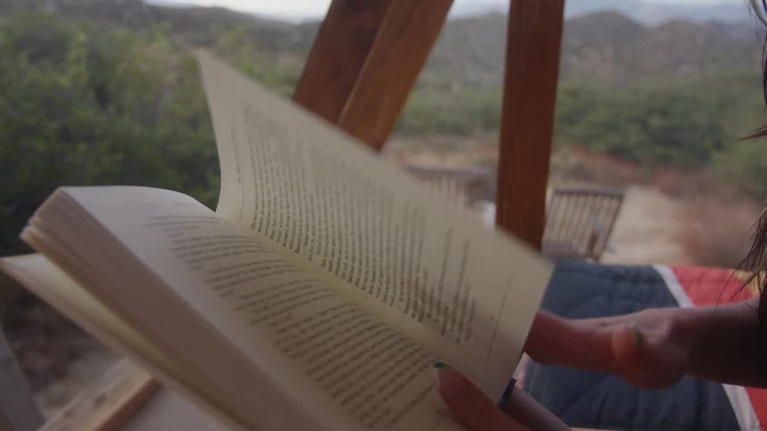 Pair of hands of a woman sitting reading a book and turning the page