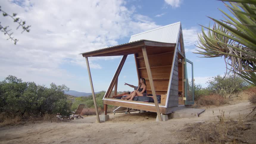Woman and a man in a camping cabin on a hill with undergrowth around