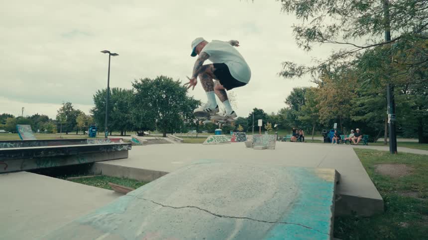 Man in cap jumping on skateboard in a trick on a track