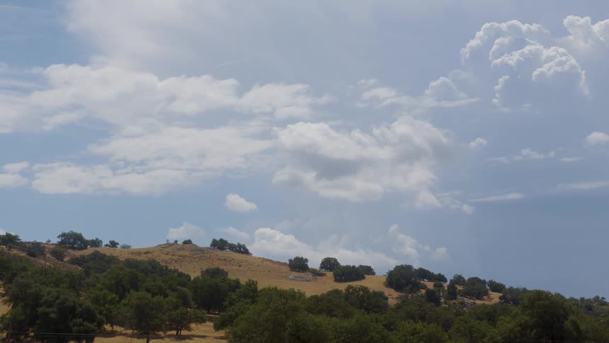 Landscape of a hill with vegetation and clouds passing by