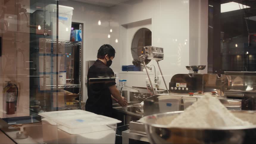 Man in mask washing his hands in restaurant kitchen