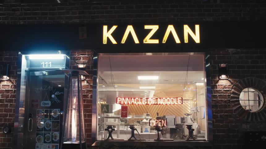 The exterior of a store with illuminated text and a large window showing the interior