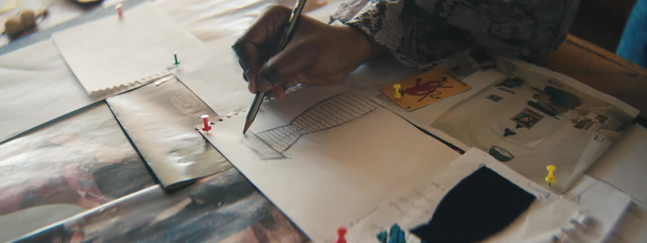 Closeup of a designers hand carefully drawing miniature dress sketches