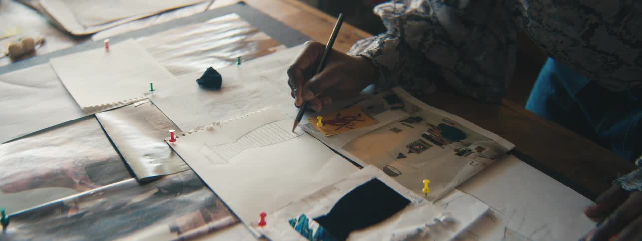 Closeup of a designers hand carefully drawing miniature dress sketches