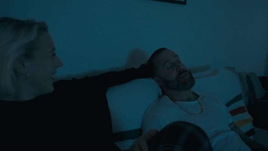 Cheerful couple sitting on the couch in the dark laughing and talking